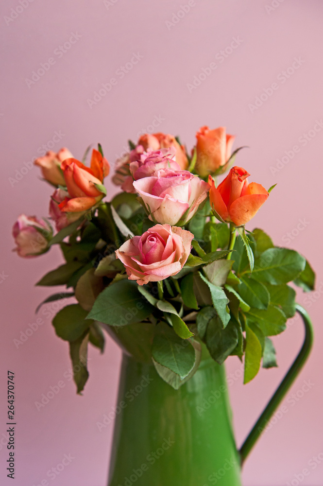 Beautiful pink and orange roses in a vase on the vintage background