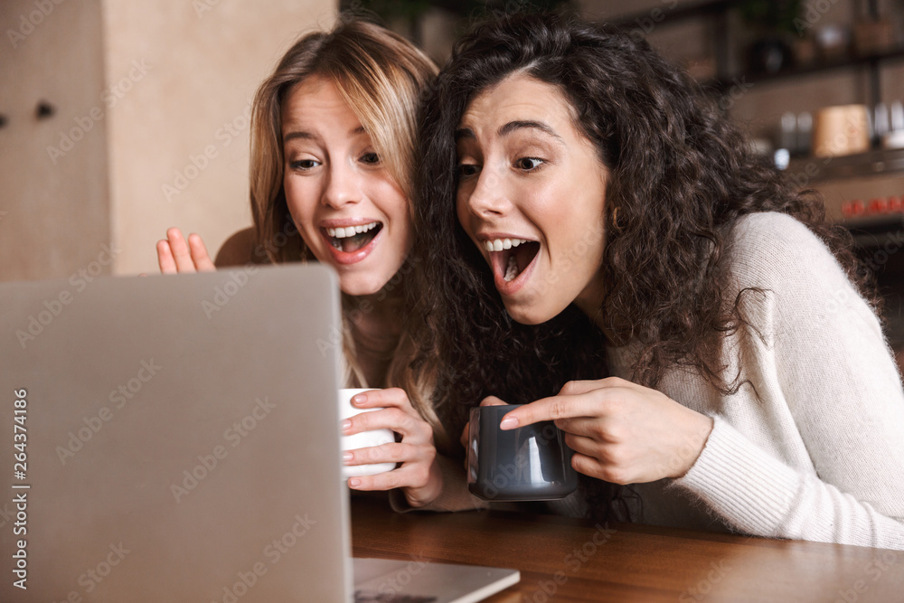 Two cheerful young girls friends sitting at the cafe table Two cheerful young girls friends sitting at the cafe table
