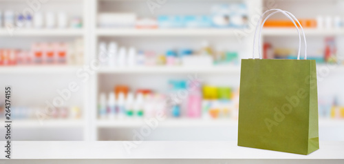 Paper bag on Pharmacy drugstore counter table with medicine and healthcare product on shelves blur background