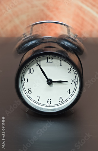 Old fashioned black alarm clock vibrating