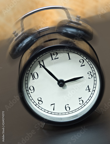 Old fashioned black alarm clock vibrating