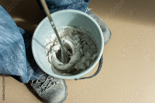 Man builder mixes gypsum putty in a bucket photo