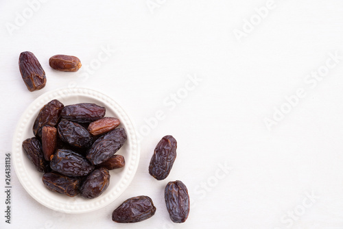 Ramadan food and drinks concept. Dates fruit and green Mint leaves in a bowl on a white wooden table background. Top view, Flat lay.