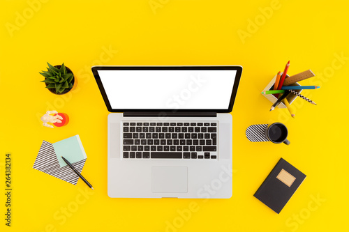 Yellow desk with laptop and supplies. Mock up. Top view. photo