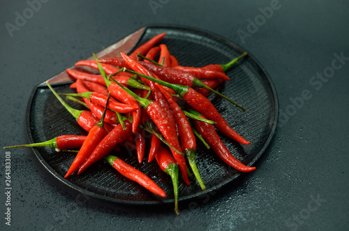 Red chilli in black plate on black background