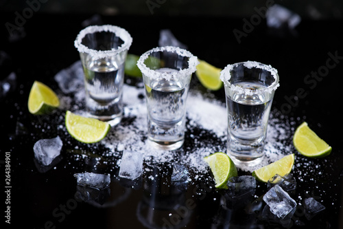 Tequila shot with lime and salt on black background