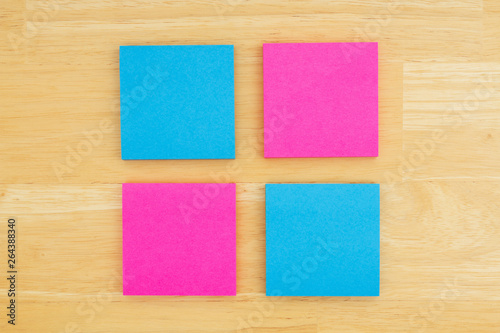 Four blank sticky notes on textured desk wood background