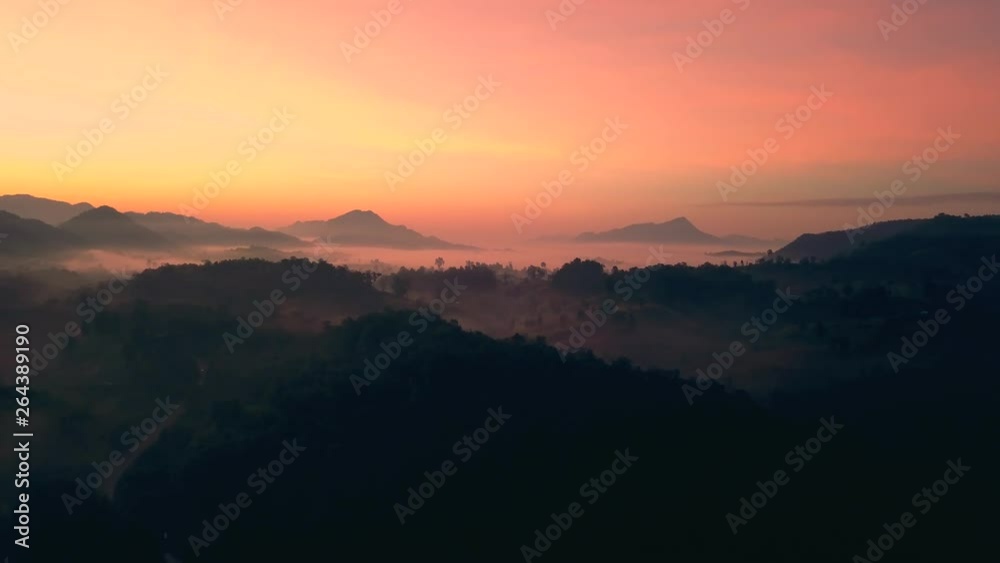 A serene aerial view of a mountain landscape covered in mist during sunrise, with soft orange and pink hues filling the sky, creating a peaceful and picturesque atmosphere. A serene aerial view of a mountain landscape covered in mist during sunrise, with soft orange and pink hues filling the sky, creating a peaceful and picturesque atmosphere.