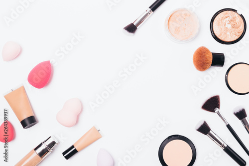 Women's cosmetics and accessories on white table, flat lay composition with an empty space in center. View from above frame of makeup products and tools.