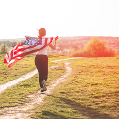 Happy women running in the field with American flag USA celebrate 4th of July