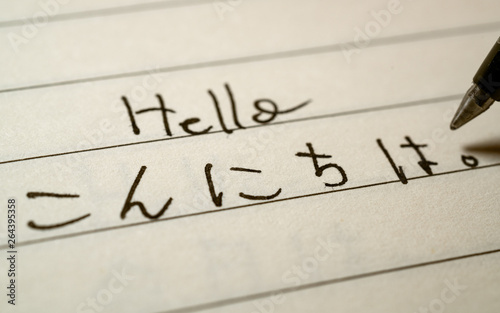 Beginner Japanese language learner writing Hello word in Japanese hiragana characters on a notebook photo