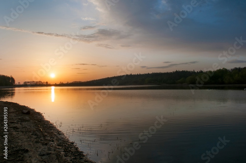 Bright sunrise above a lake with reflection and colorful clouds