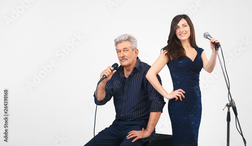 Musical blowing, two singers, man and girl holding microphones, singing, smiling, looking at camera, isolated on white background