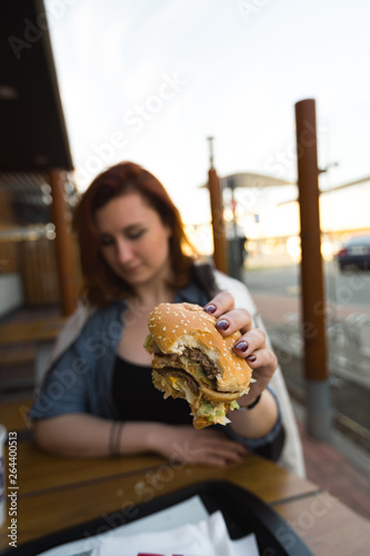 Hamburger close up - Young Woman eating in Fast Food Restaurant - Cheeseburger  medium fries and soda