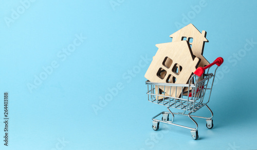 Shopping cart and house on a blue background. Buying and selling real estate. Copy space for text. photo