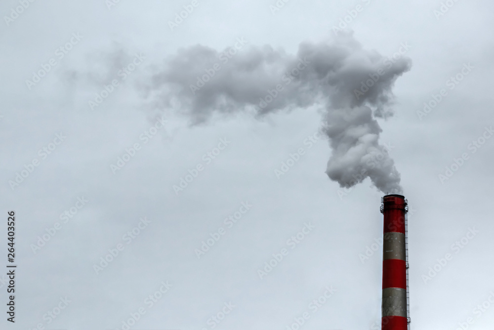 The pipe from which the smoke goes against the gray sky. The concept of air pollution, CO2, carbon dioxide gas, exhaust gases.