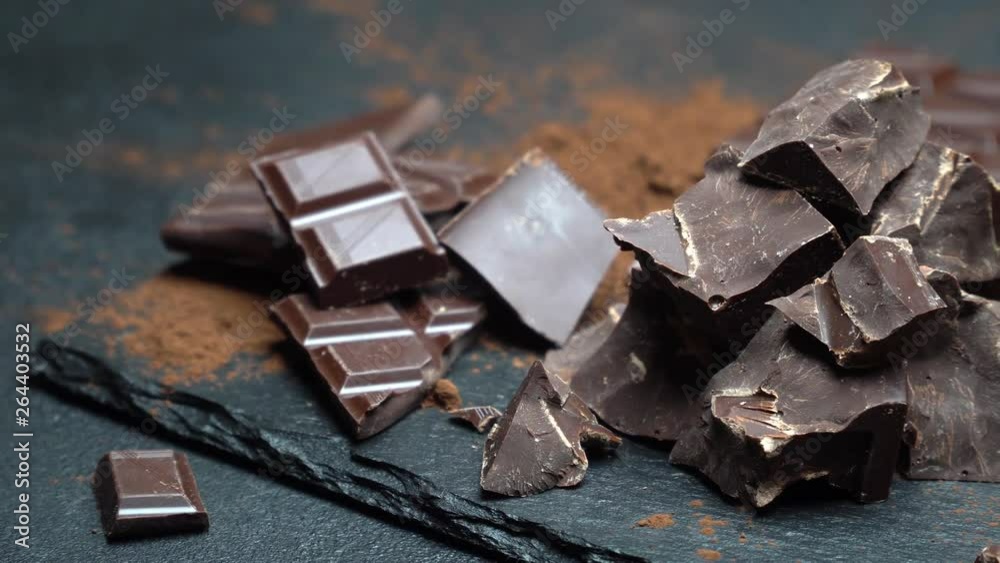 Dark or milk organic chocolate pieces on dark concrete background Dark or milk organic chocolate pieces on dark concrete background