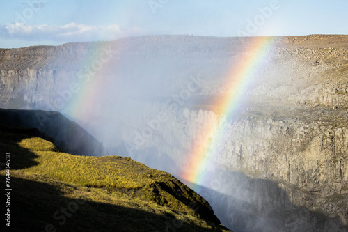 Сanyon of the river of Derrifoss, waterfall in Vatnajökull National Park in Northeast Iceland, the most powerful waterfall in Europe in sun light with double rainbow. Green grass and canyon gorge.