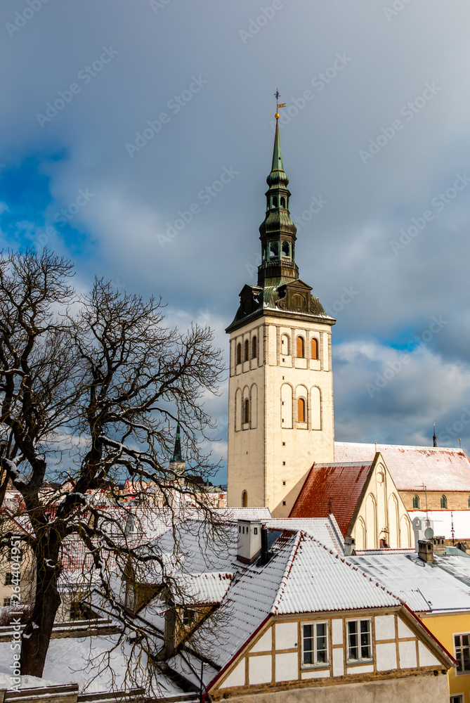 Tallinn city view with St Nicholas Church and red roofs in snow on a sunny day. Ancient european town cityscape