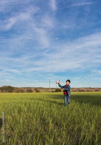 Boy running with a plane in a park.
