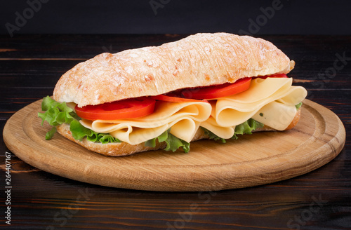 Ciabatta sandwich with lettuce , prosciutto and  cheese on wooden board