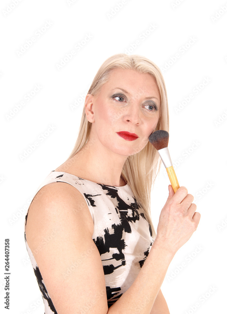 Beautiful blond woman fixing her makeup with a brush Beautiful blond woman fixing her makeup with a brush