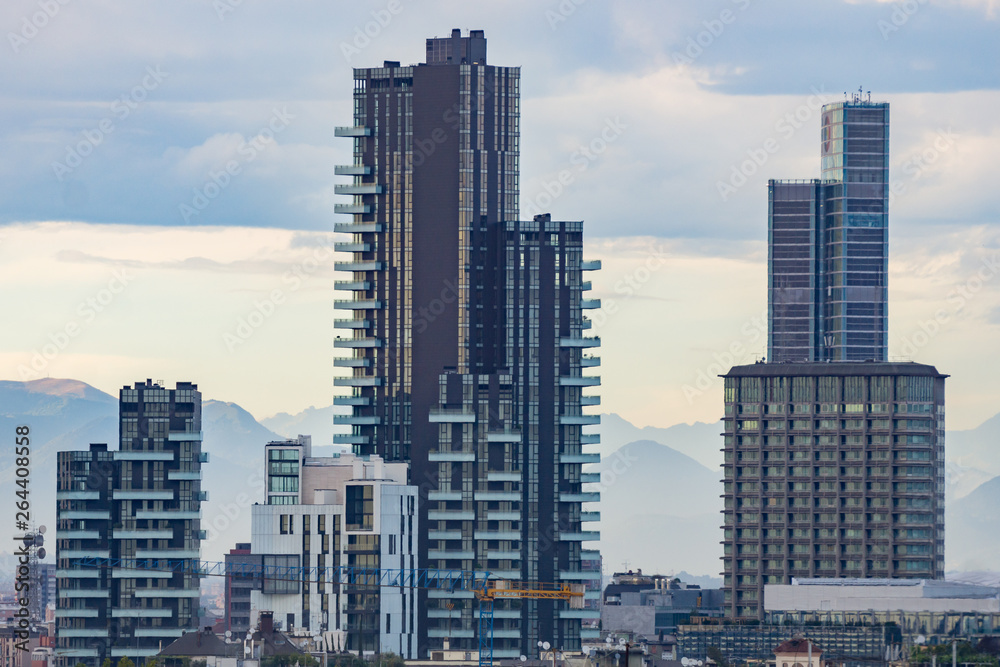 City skyline with skyscrapers of Porta Nuova district in Milan, Italy, Europe. Mountains behind the tall buildings.