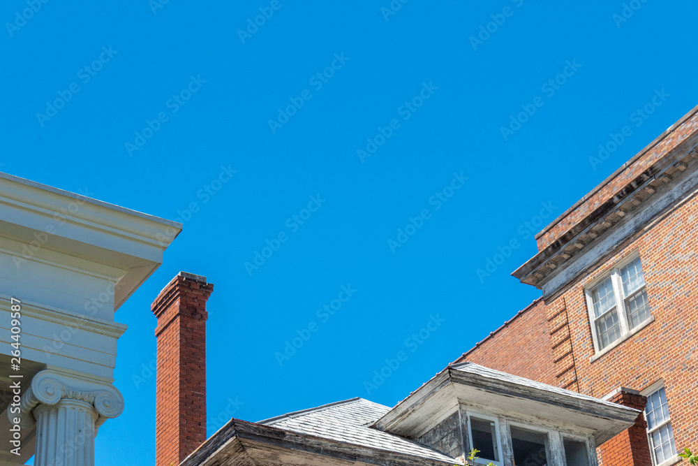 Mix of architecture with Ionic columns, abandoned house with very tall chimney, and brick apartment buildings, horizontal aspect