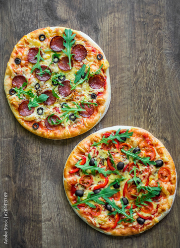 Pepperoni Pizza and Pizza with Mozzarella cheese, Tomatoes, pepper, olive, Spices and Fresh arugula. Pizza Margherita or Margarita on wooden table background