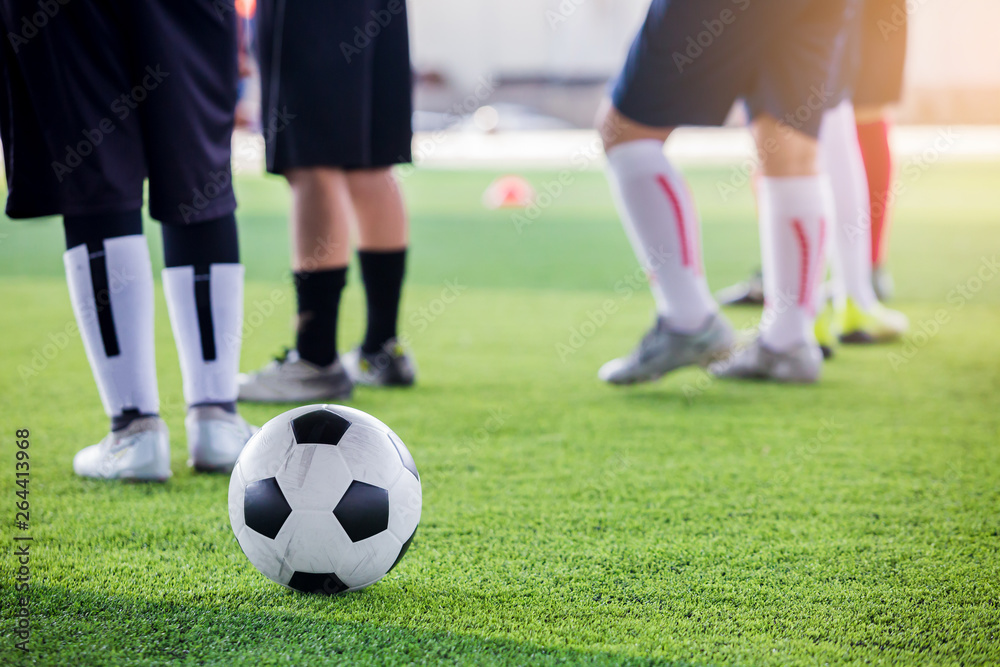 soccer ball on green artificial turf with blurry soccer players