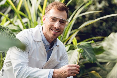 Obraz na płótnie selective focus of smiling handsome scientist in white coat and goggles taking p