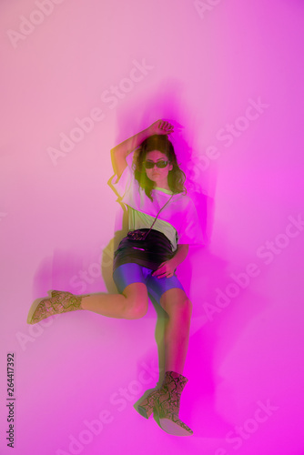 motion blur of young woman in sunglasses lying on purple