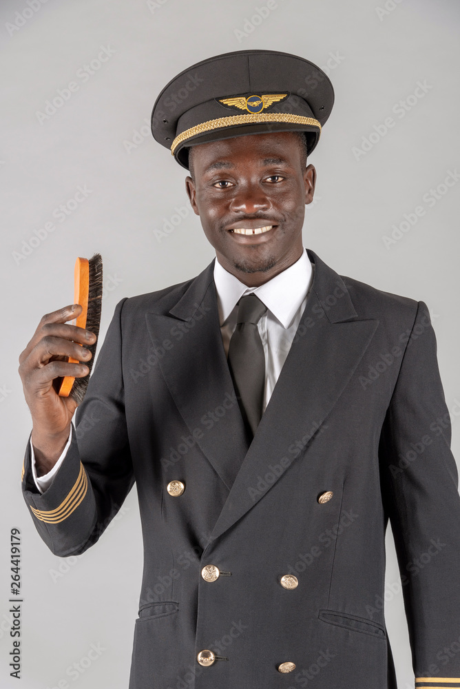 London, UK. April 2019. An airline pilot brushing his captain's uniform London, UK. April 2019. An airline pilot brushing his captain's uniform