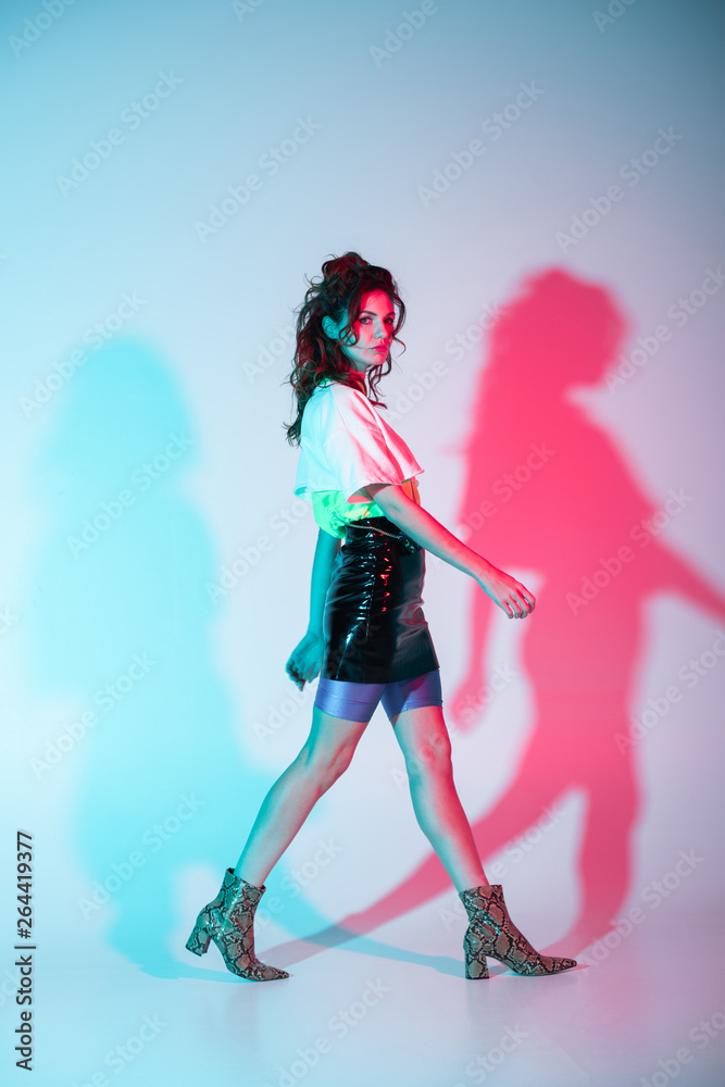 attractive curly young woman looking at camera and walking on blue with illumination attractive curly young woman looking at camera and walking on blue with illumination