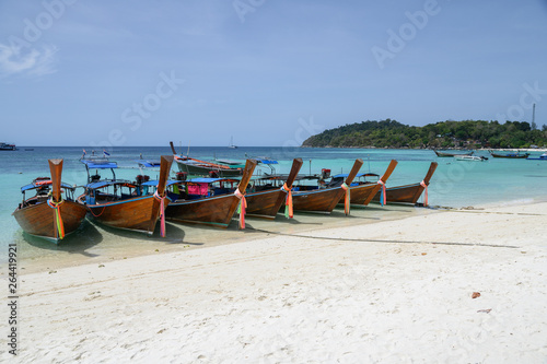 Fototapeta Naklejka Na Ścianę i Meble -  Long-tail wooden boats anchored on white beach in tropical sea