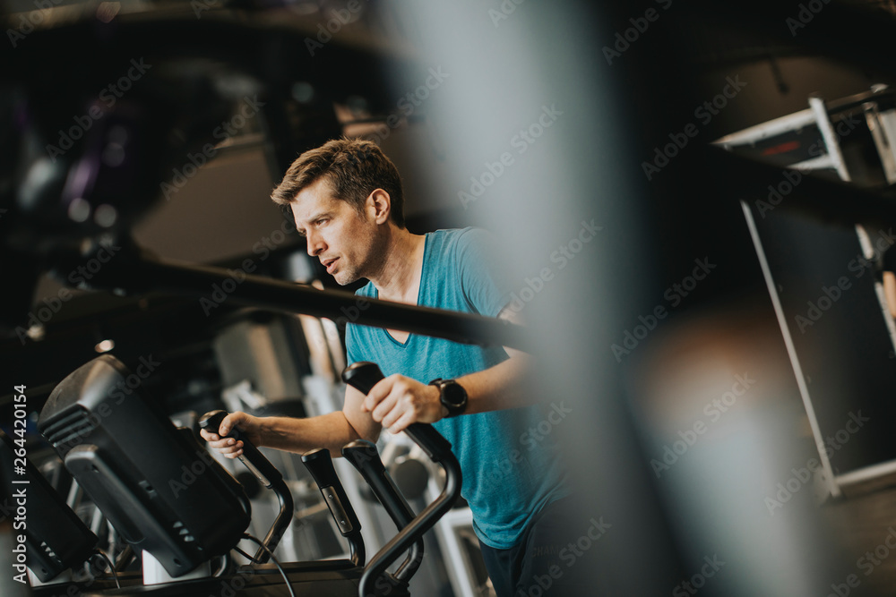 Man doing exercise on elliptical cross trainer in sport fitness gym club Man doing exercise on elliptical cross trainer in sport fitness gym club