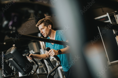 Man doing exercise on elliptical cross trainer in sport fitness gym club © BGStock72