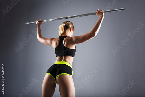 Butts and the back of a beautiful young woman fitness instructor posing against a gray background. Concept of sports lifestyle