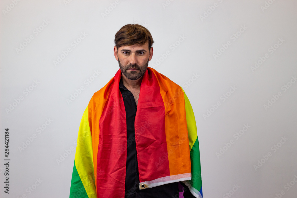 Portrait of handsome young man with gay pride movement LGBT Rainbow flag and brown hair thoughtful, looking at the camera. Isolated on white background. Portrait of handsome young man with gay pride movement LGBT Rainbow flag and brown hair thoughtful, looking at the camera. Isolated on white background.