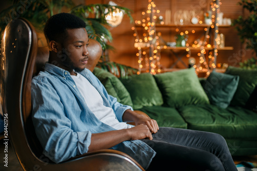 Canvas Print Black man sitting in a comfortable leather chair