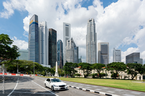 Photography Taxi cab driving in road in Singapore downtown with Singapore skyscrapers building in background