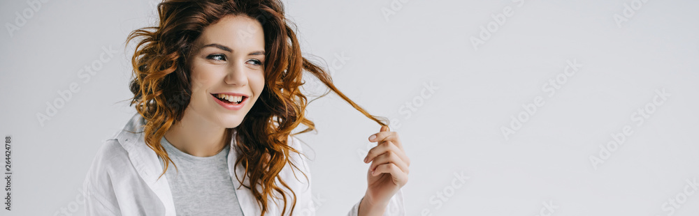 panoramic shot of cheerful young woman touching red hair on white panoramic shot of cheerful young woman touching red hair on white