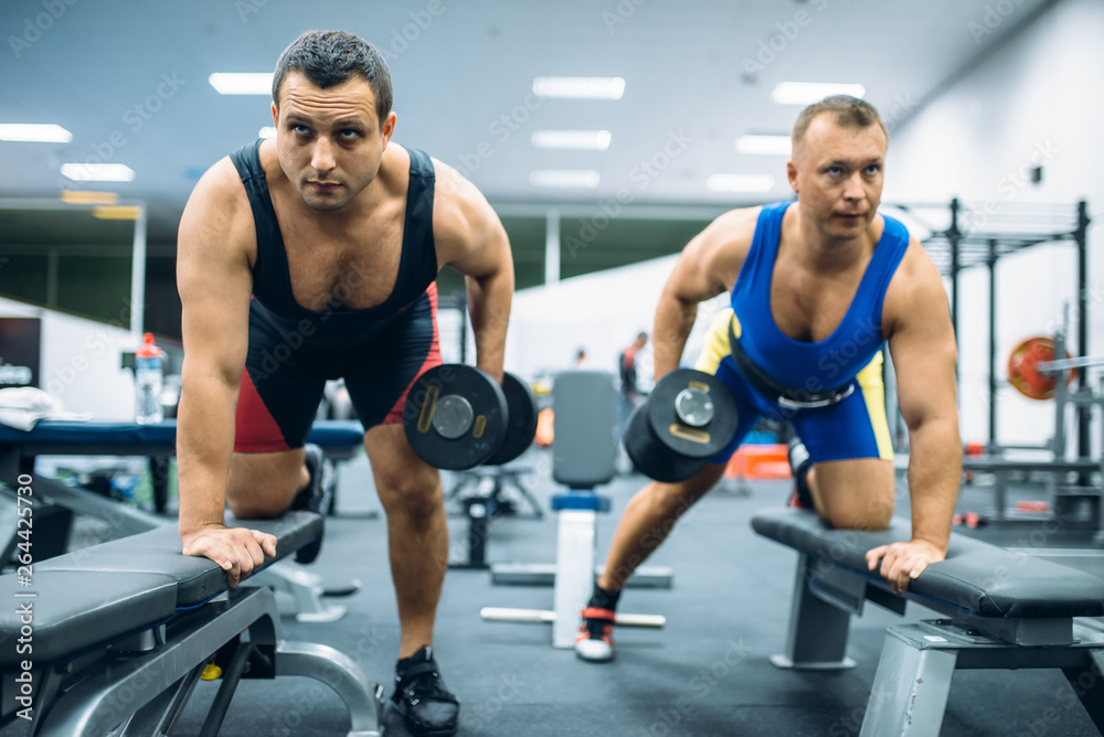 Two weightlifters doing exercise with dumbbells Two weightlifters doing exercise with dumbbells