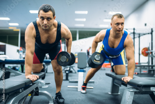 Fototapeta Naklejka Na Ścianę i Meble -  Two weightlifters doing exercise with dumbbells