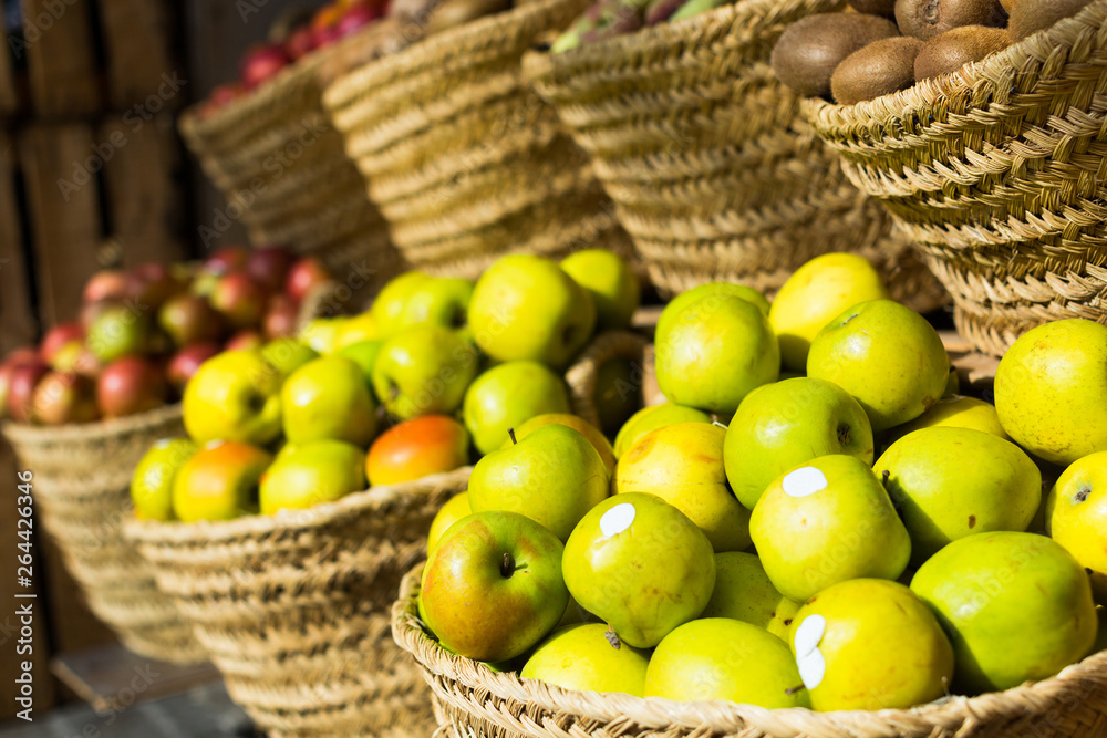 green farm apples in wicker baskets on counter in market green farm apples in wicker baskets on counter in market
