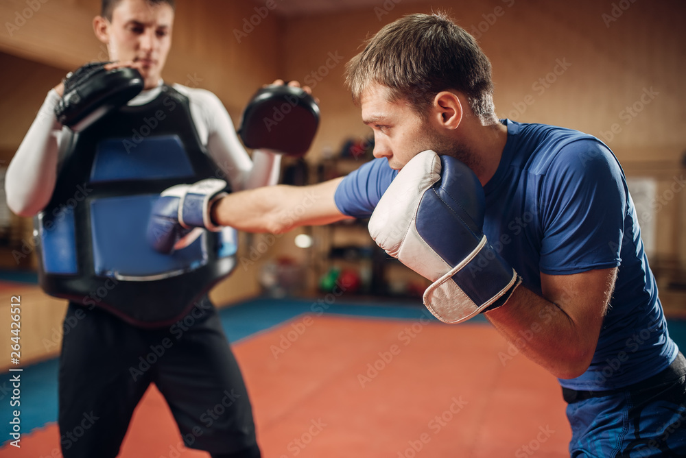 Male kickboxer in gloves practicing hand punch