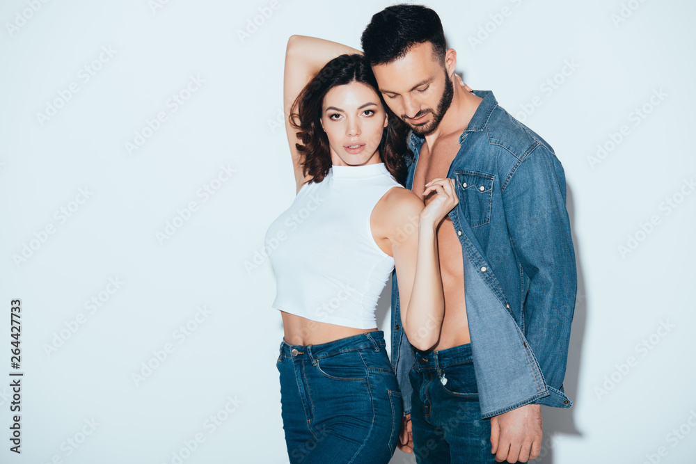 stylish couple in jeans standing together on grey stylish couple in jeans standing together on grey