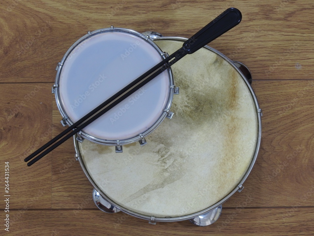 Fototapeta premium Two Brazilian percussion musical instruments: pandeiro (tambourine) and tamborim with drumstick on a wooden surface. The instruments are widely used to accompany samba, a popular Brazilian rhythm.
