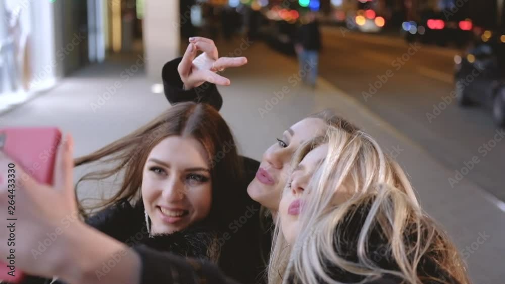 Girls night out party. Beautiful female friends having fun, taking selfie on the street with blur city lights.