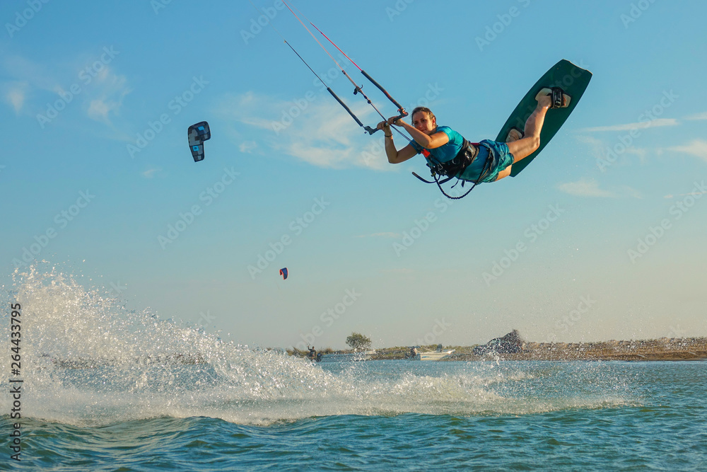 LOW ANGLE: Happy young woman jumps high in the air while kiteboarding in Greece.